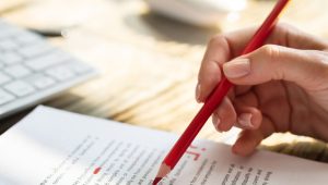 Close-up Of A Person's Hand Marking Error With Red Marker On Document